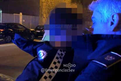 Un policía local de Sevilla lleva en brazos al niño extraviado.