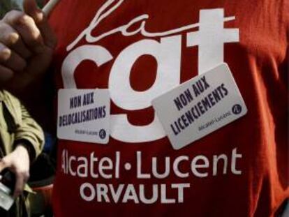 Un trabajador luce en su camiseta pegatinas con lemas contra la deslocalización y los despidos durante una manifestación en París. EFE/Archivo