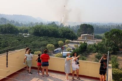 Vecinos observan como un helicóptero intenta extinguir el incendio forestal en Xerta, uno de los pueblos confinados en la provincia de Tarrragona, este martes.