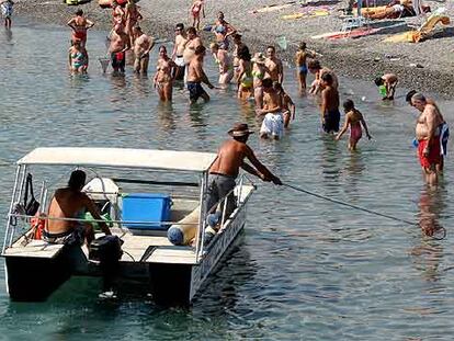 Un operario recoge medusas frente a la playa de Salobreña (Granada) el pasado lunes.