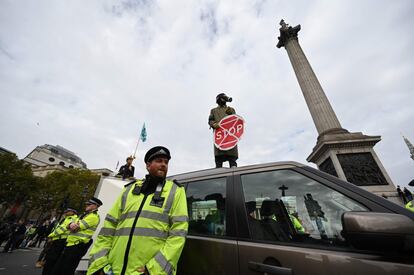 Un activista del grupo Extinction Rebellion con una máscara de gas encima de un coche en Trafalgar Square, Londres.