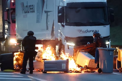 Agentes de policía retiran contenedores de basura en llamas y otros objetos colocados por manifestantes para bloquear el tráfico en la circunvalación de Nantes.