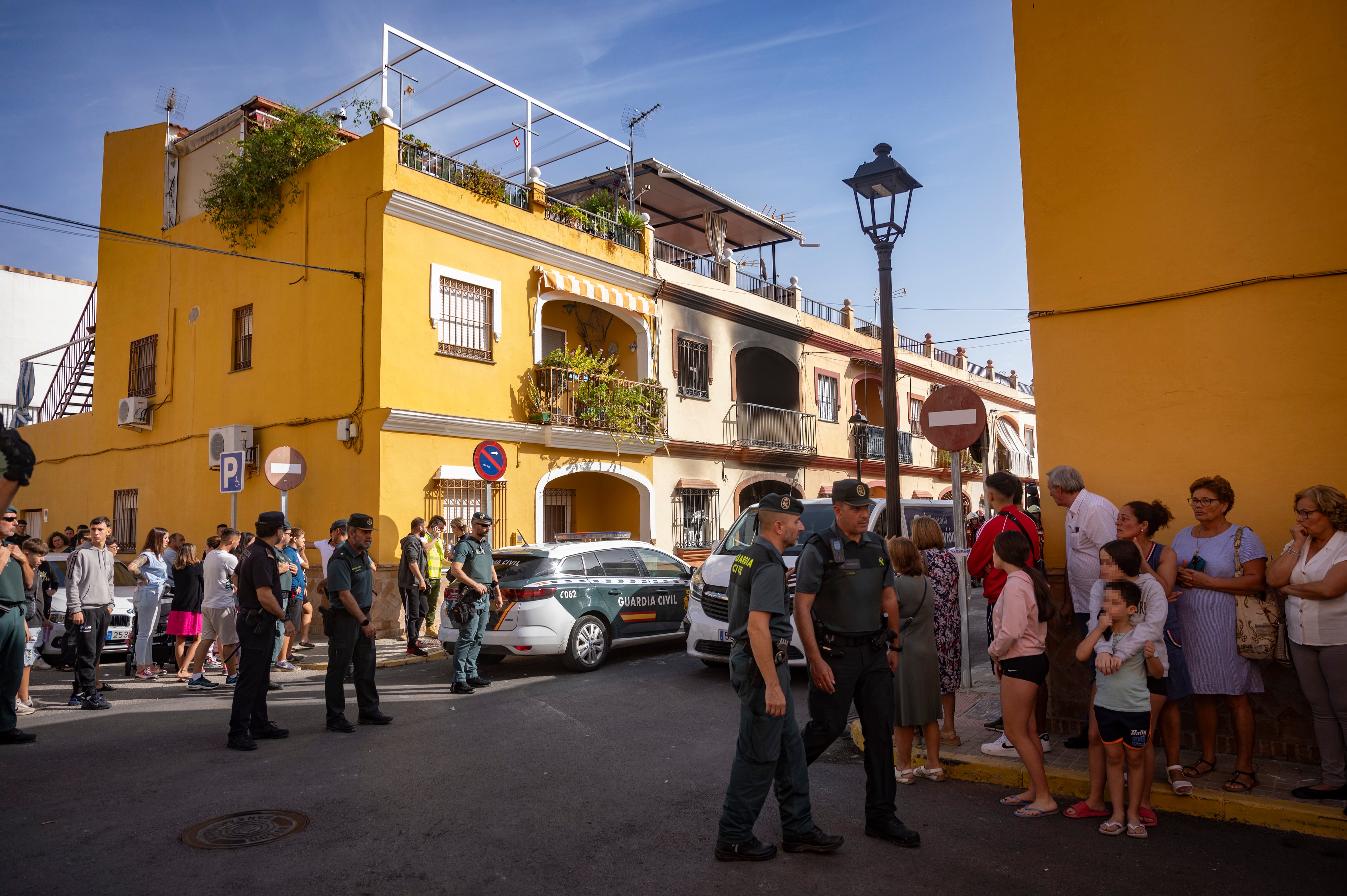 Vecinos y agentes de la Guardia Civill en la  calle Fernando Martín de la localidad sevillana de Guillena, donde han fallecido este domingo cuatro personas de la misma familia. 