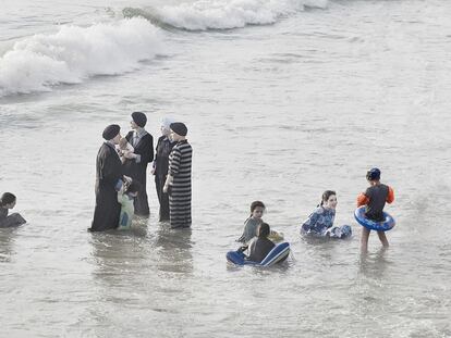 La ropa les impide adentrase en el mar, por eso la mayoría se queda en la orilla charlando.