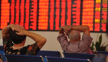 Dos inversores observan un panel con cotizaciones bursátiles en Fuyang (China).