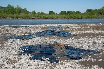 In this photo provided by Alexis Bonogofsky, petroleum products cover areas along the banks of the Yellowstone River near Columbus, Mont., July 1, 2023, following a freight train wreck last week in which tank cars fell into the river when a bridge collapsed.