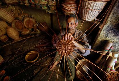 Un artesano teje una canasta hecha de ramas de sauce en su taller a las afueras de Srinagar (India).