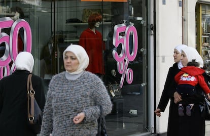 La época de rebajas en las tiendas se respeta incluso en un país en plena guerra civil. En la imagen, mujeres sirias pasan ante una tienda que anuncia descuentos en un zoco de Damasco, este pasado 13 de febrero.