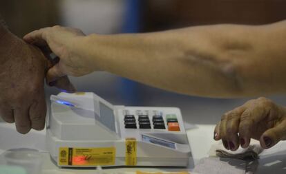 Mesária colhe digital de eleitor na eleição municipal de 2016 em Niterói.