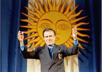 Carlos Saúl Menem saluda durante un mitin de la campaña electoral, desde una tribuna decorada con una gigantesca bandera argentina, el 9 de mayo de 1995.