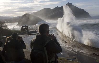 Varios curiosos fotografían las olas a la altura de 'El Peine de los Vientos' de San Sebastián.