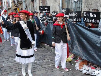 Componentes de la compañía mixta Jaizkibel desfilen en Hondarribia entre un pasillo de plásticos negros.