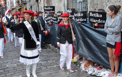 Componentes de la compañía mixta Jaizkibel desfilen en Hondarribia entre un pasillo de plásticos negros.