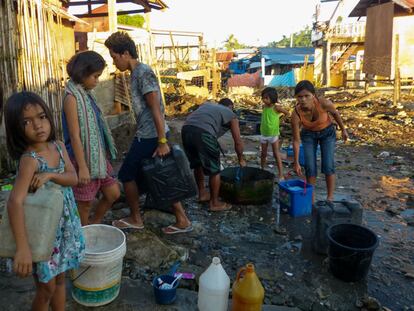 Un grupo de niños y jóvenes recoge agua de un pozo instalado a las orillas de la localidad filipina de Tacloban, en una zona arrasada por un tsunami con el paso del tifón Haiyán en noviembre de 2013.