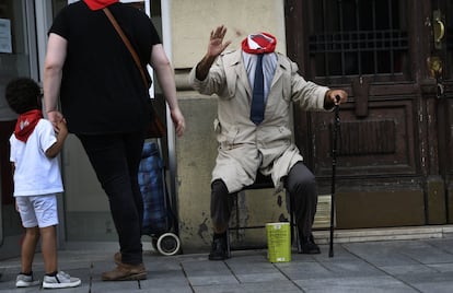 Un artista callejero disfrazado del hombre sin cabeza saluda a una mujer y a un niño tras darle unas monedas, en la avenida de Carlos III.