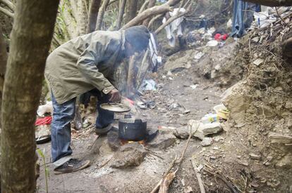 Un ciudadano camerunés prepara la comida en el bosque de Belyounech, entre Tánger y Ceuta.