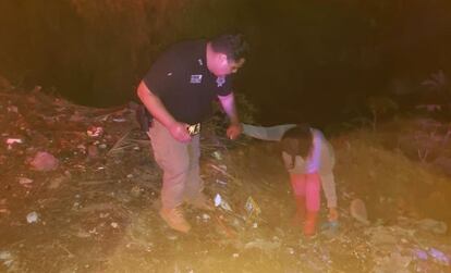 Un policía ayuda a una mujer a salir de un canal de aguas negras en Ecatepec de Morelos.