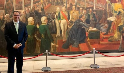 Lafayette Andrada posa no Itamaraty, em frente à obra que mostra a coroação de Dom Pedro I