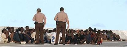 Dos policías estadounidenses vigilan a decenas de inmigrantes haitianos en una autopista cercana a la costa de Miami.