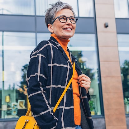 Una mujer elegante de unos 50 años caminado por la calle.