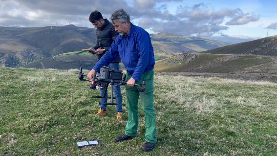 Dos hombres se preparan para volar un dron sobre la granja 'El Carbayal', en Asturias.