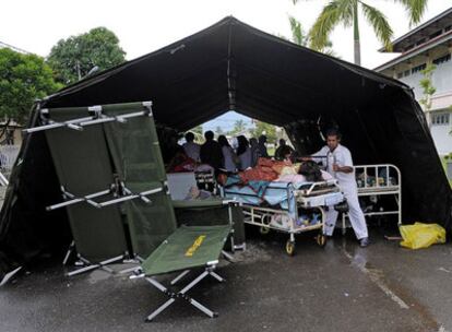 Un médico indonesio traslada en una cama a un herido del terremoto en un hospital de campaña en Padang.