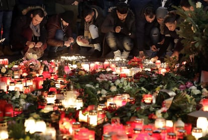 Varias personas encienden velas en la entrada al mercado de Navidad en el que un camión arrolló a la multitud en Berlín.