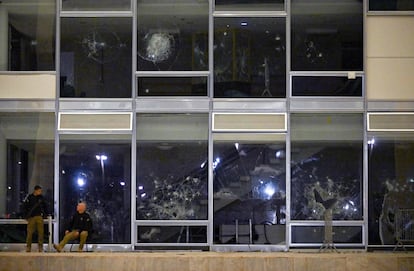 Dos agentes de la Policía Judicial hablan junto a las ventanas rotas de la Corte Suprema después de la invasión. 