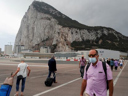 Varias personas cruzan a pie la pista del aeropuerto de Gibraltar, a la entrada de la colonia.