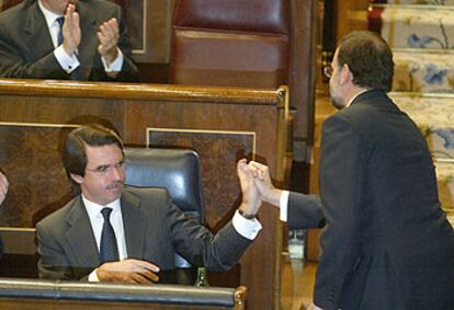 José María Aznar felicita sentado en su escaño a Mariano Rajoy por su intervención en el pleno ayer.