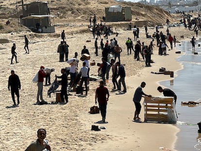 Decenas de palestinos recuperaban en el mar ayuda humanitaria lanzada en paracaídas, este lunes en Gaza.