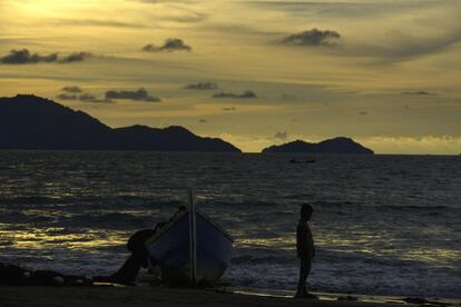 Un niño se permanece junto a un barco de pesca en la playa de Banda Aceh, en la provincia de Aceh, localizada en el norte de la isla de Sumatra (Indonesia).