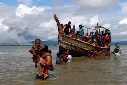 Un grupo de refugiados rohingya cruza en barco desde Myanmar (al fondo, con humo) a Bangladés, este lunes.