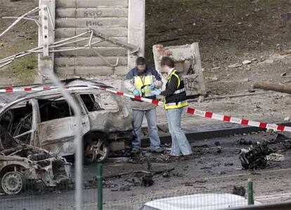 La policía acude para inspecionar el coche bomba y los destrozos provocados por él.