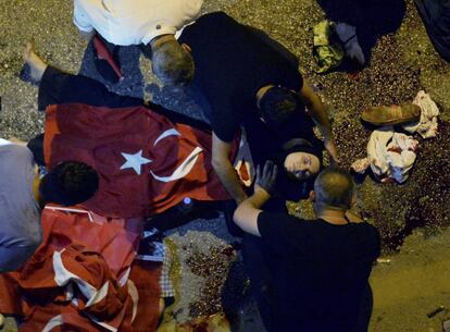 Una mujer herida tapada con una bandera turca, es atendida por un grupo de personas cerca de un puesto militar en Ankara (Turquía).