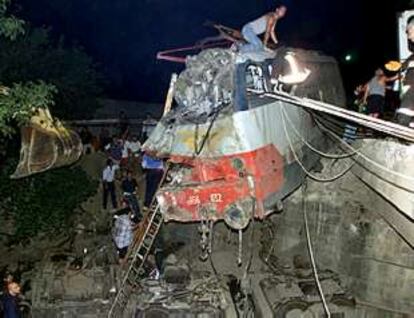 Varias personas buscan víctimas en el interior de la locomotora del tren accidentado.