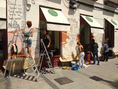 El colectivo La Rueda Invertida trabajando en el dibujo que cubre la fachada del bar Donde da la vuelta el viento.