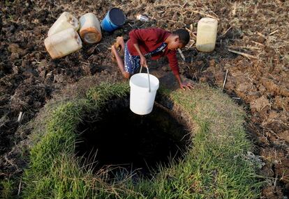 Una mujer saca agua de un pozo en uno de los suburbios de Harare, capital de Zimbabue.