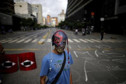Un manifstante, con una máscara adornada con rosarios, junto a una barricada durante la huelga general de 48 horas.