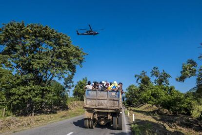 Un grupo de hondureños es llevado en un camión de materiales. Arriba, un helicóptero de la policía federal mexicana vigila su trayecto.