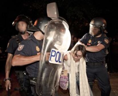 Miembros de la policía nacional retienen a una joven durante el choque con los indignados frente al Ministerio del Interior.