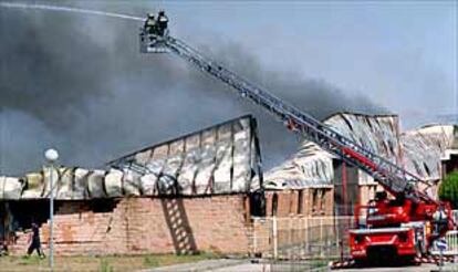 Un grupo de bomberos de la Comunidad de Madrid, ayer, en el almacén de papel incendiado en Alcalá.