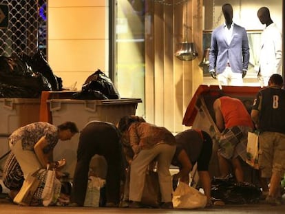 Varias personas buscan comida y enseres el pasado mes de junio en bolsas y contenedores ubicados ante un centro comercial de Madrid.