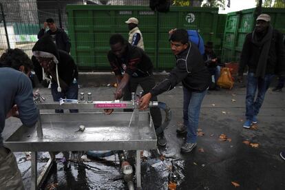 Migrants wash themselves from a sink installed in a street of Paris on October 11, 2017. 
Unprecedented waves of migration are affecting the world today with record numbers of people escaping war-torn regions, poverty, persecution and natural disasters. That influx of people is just a fraction of the record 65.6 million people who were either refugees, asylum seekers or internally displaced around the world by the end of 2016, according to the UN refugee agency. / AFP PHOTO / CHRISTOPHE ARCHAMBAULT