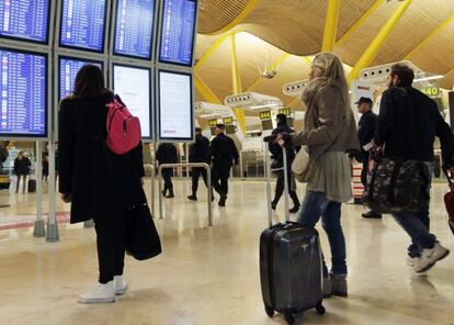 Los pasajeros consultan los monitores informativos en la T4 del aeropuerto de Barajas, en Madrid en una imagen de archivo.