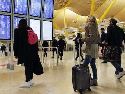 Los pasajeros consultan los monitores informativos en la T4 del aeropuerto de Barajas, en Madrid en una imagen de archivo.