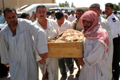 Un grupo de iraquíes transportan el cadáver de uno de los civiles asesinados en una estación de autobuses al norte de Bagdad.