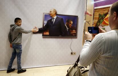 Un joven posa para una foto con un poster del presidente Vladimir Putin y el presidente estadounidense Barack Obama, el 3 de enero de 2016.  