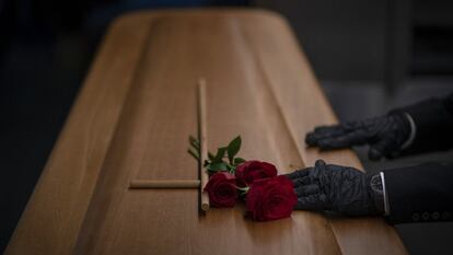 Un trabajador de una funeraria prepara un féretro de una víctima de covid antes de su incineración, en un tanatorio de Girona.