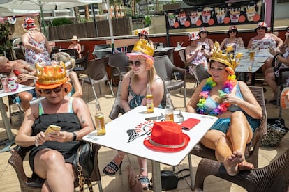 Turistas británicas, con coronas y orejas postizas por la coronación del rey Carlos de Inglaterra, en una terraza de Benidorm.